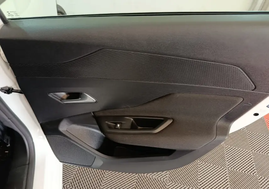 Vue intérieure côté gauche de la porte avant blanche de la Peugeot 308 avec panneau noir texturé et commande de fenêtre.