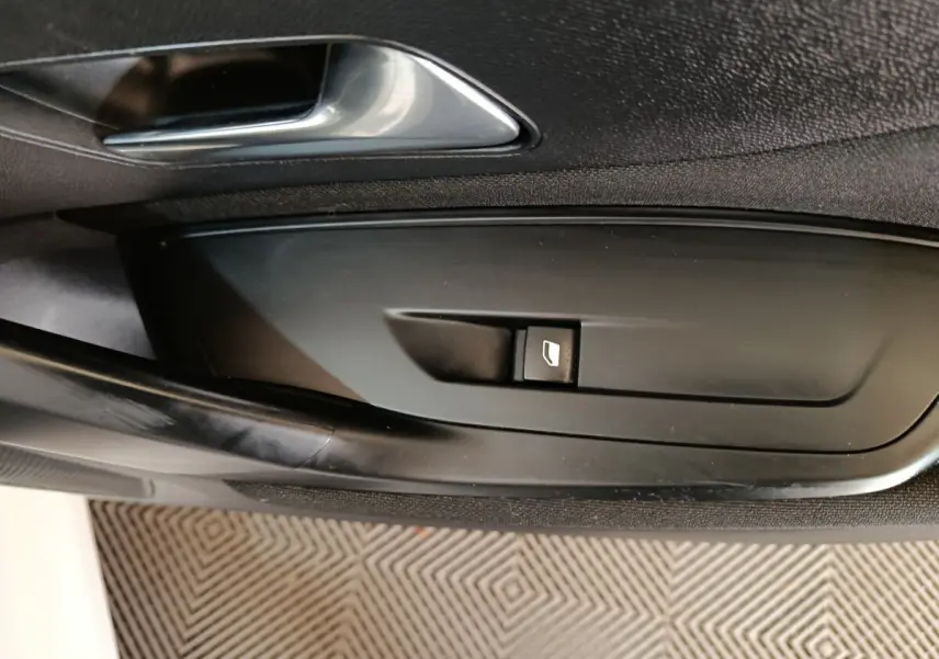 Gros plan sur la commande de lève-vitre côté conducteur de la Peugeot 308 blanche, intérieur noir.