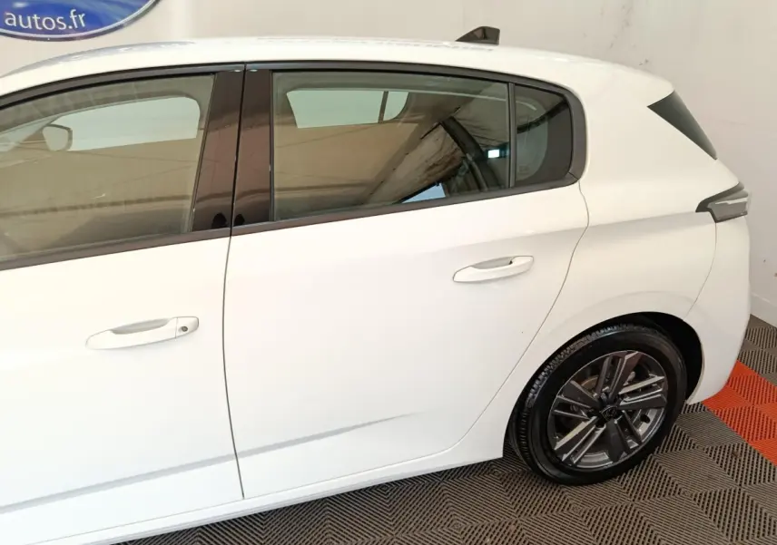 Vue latérale droite sur une Peugeot 308 blanche de 2022, mettant en valeur les vitres teintées et les jantes alliage.
