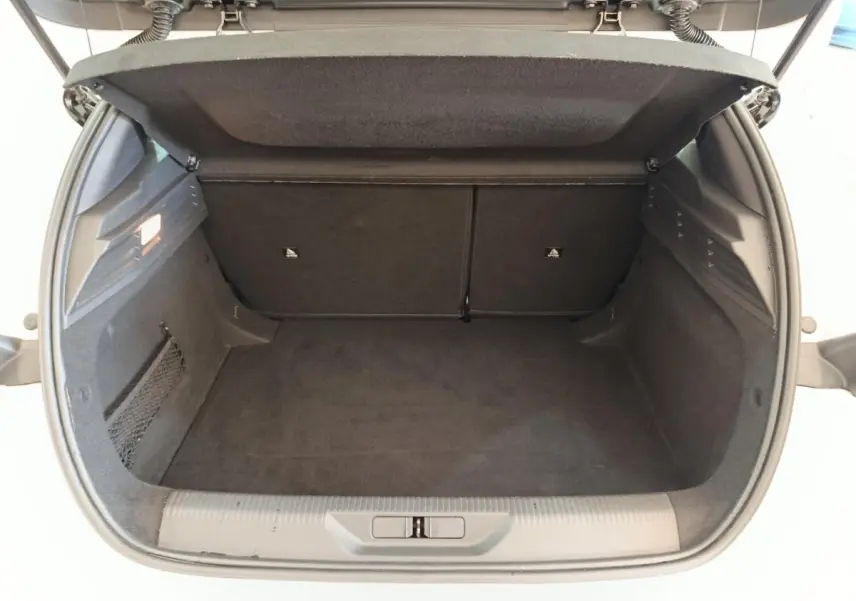 Coffre ouvert vu de l'arrière d'une Peugeot 308 blanche, montrant un espace de chargement propre et spacieux.