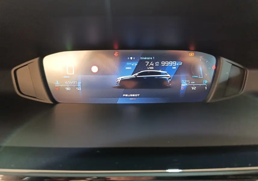 Affichage digital du tableau de bord de la Peugeot 308 blanc, montrant les informations de conduite et consommation.