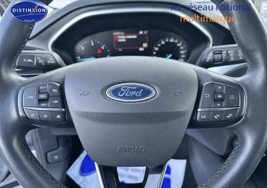 Gros plan sur le volant Ford d'une Focus 2019, montrant les commandes intégrées et le tableau de bord numérique.