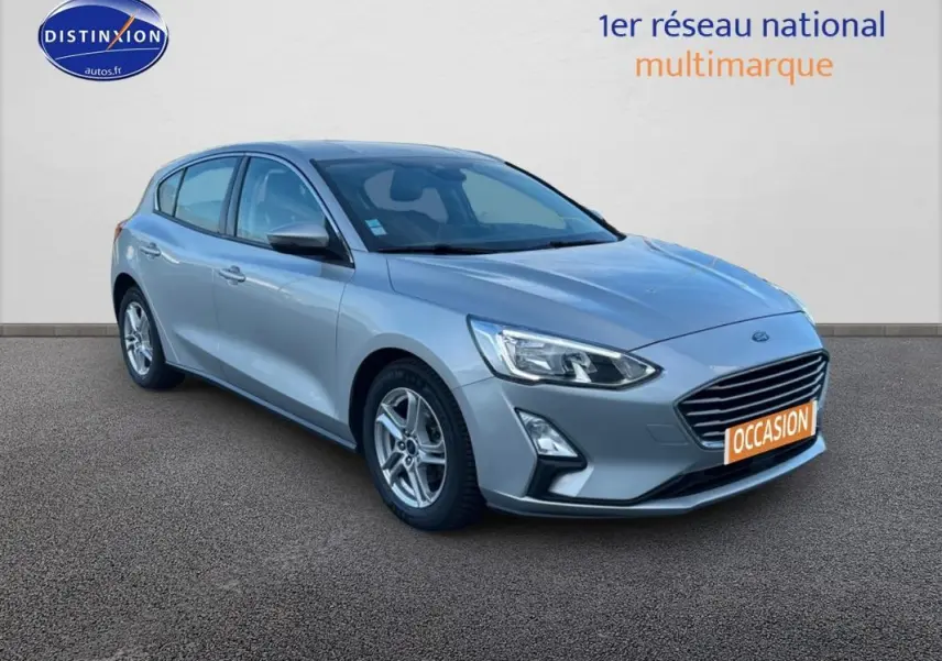 Ford Focus gris clair vue 3/4 avant droit avec jantes alliage et plaque "OCCASION" visible.