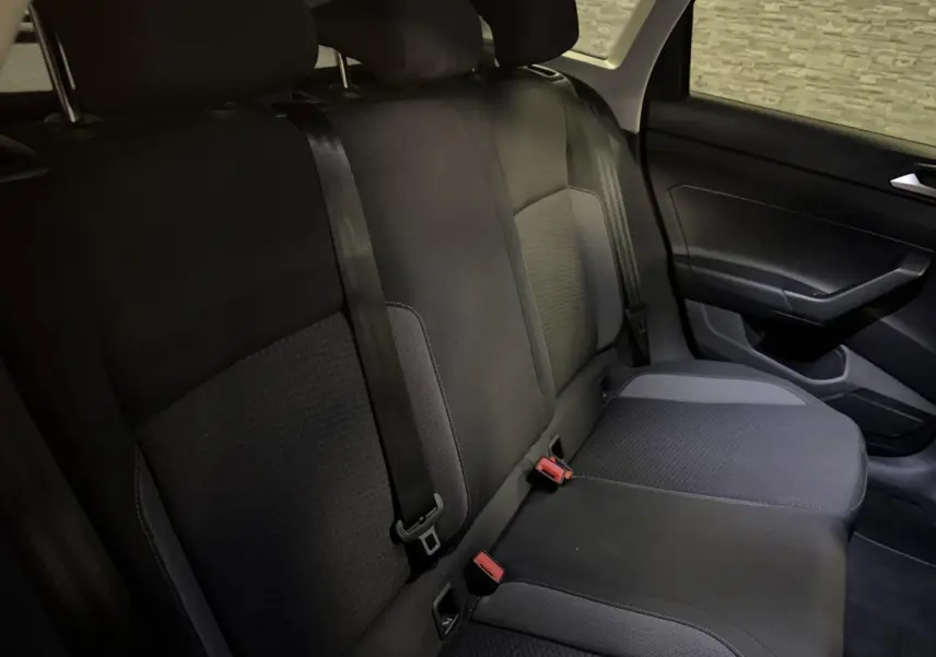 Vue intérieure de la banquette arrière en tissu gris foncé du Volkswagen Taigo 2024 côté droit avec ceintures de sécurité visibles.