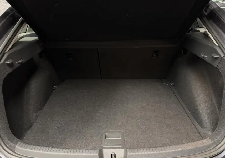 Coffre ouvert vu de l'arrière d'un Volkswagen Taigo gris, montrant un espace de chargement propre et spacieux.
