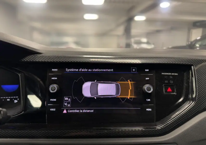 Vue rapprochée de l'écran tactile central du Volkswagen Taigo gris 2024 affichant l'aide au stationnement active.