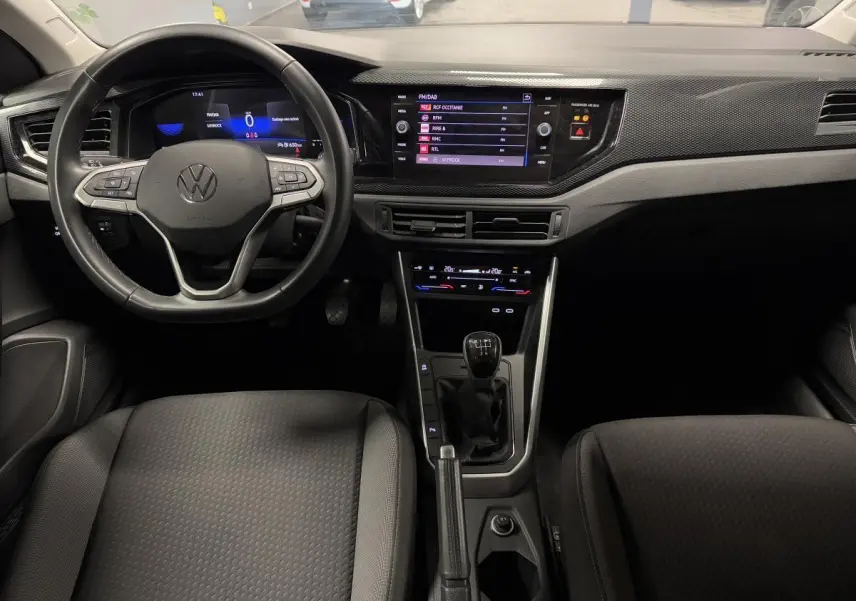 Vue intérieure avant du Volkswagen Taigo 1.0 TSI 95 Life 2024, tableau de bord avec écran tactile et levier de vitesse manuel.