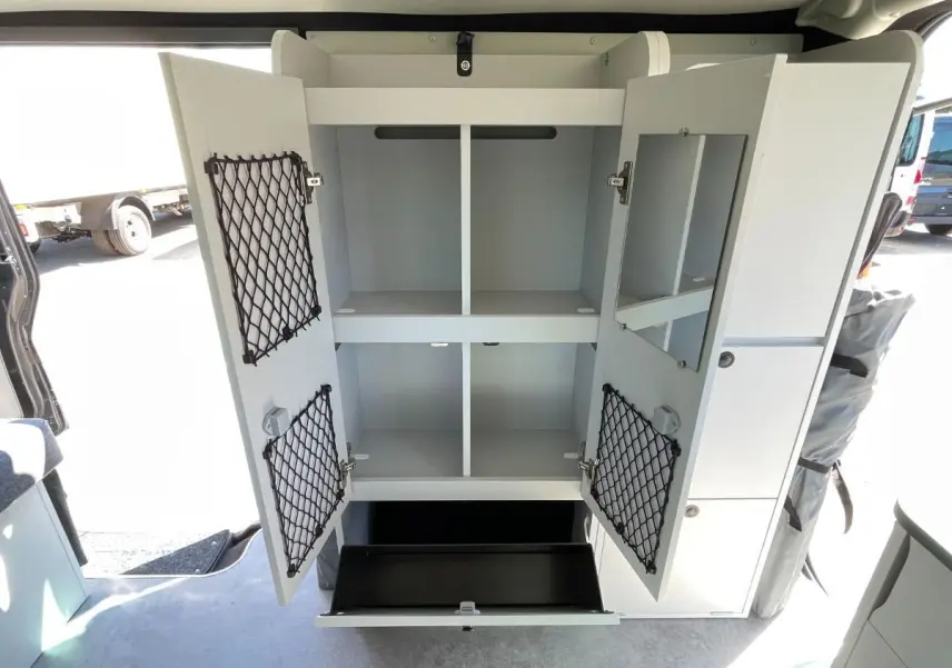 Vue intérieure du Renault Trafic Fourgon gris Comète montrant un meuble de rangement blanc ouvert avec filets et tiroir.