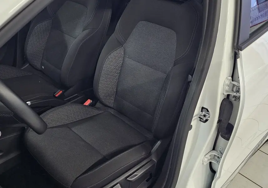 Vue intérieure côté conducteur de la Renault Clio blanche glacier 2020, avec sièges tissu gris et noir détaillés.