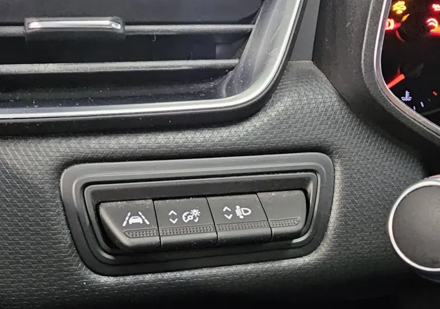 Gros plan sur les commandes d'assistance à la conduite dans l'habitacle noir texturé d'une Renault Clio blanche 2020.