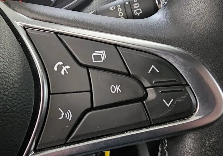 Gros plan sur les commandes multifonctions du volant noir de la Renault Clio blanche Glacier version Business 2020.