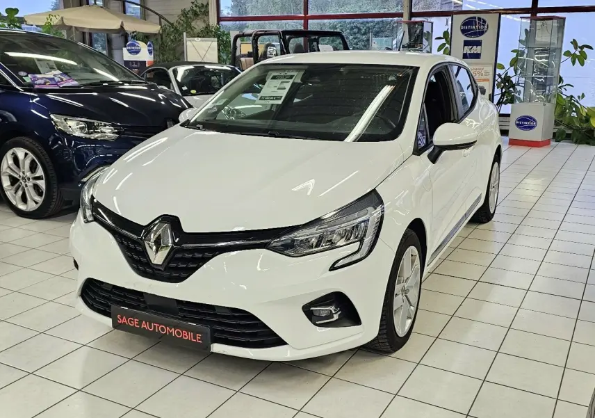 Renault Clio blanc glacier vue 3/4 avant droit en showroom avec phares LED et calandre noire brillante.