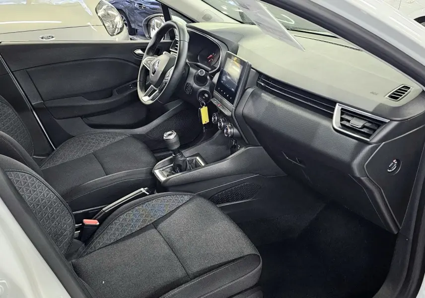 Intérieur côté conducteur d'une Renault Clio blanche glacier 2020 avec sièges noirs et tableau de bord moderne.