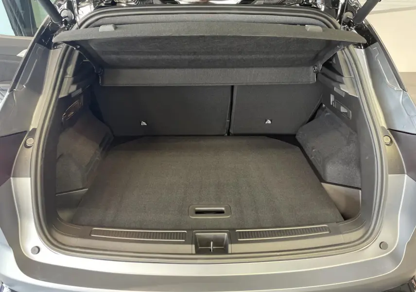Coffre ouvert vu de l'arrière d'un Renault Austral gris satin mat avec intérieur de coffre noir et cache-bagages relevé.