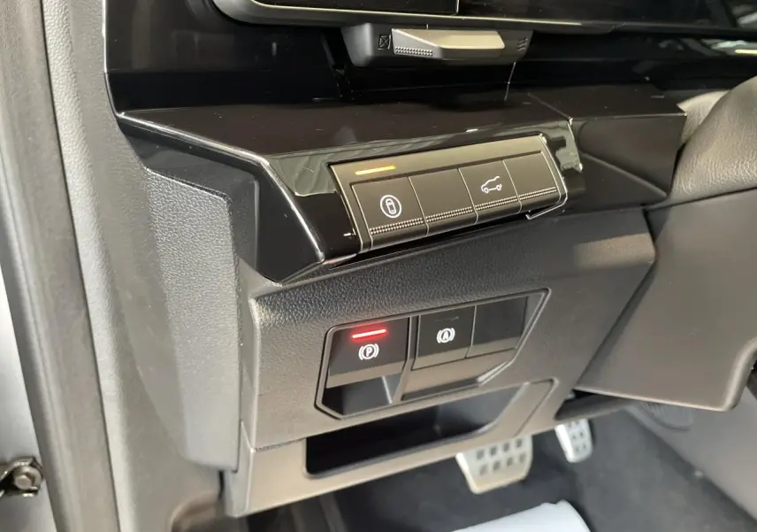 Gros plan sur les commandes du frein de parking électrique et ouverture du hayon dans l'habitacle du Renault Austral 2025.