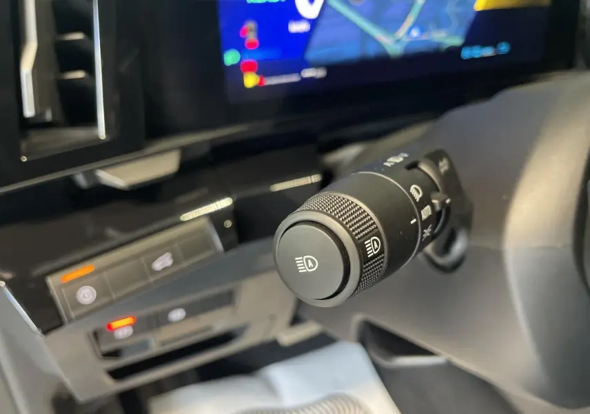 Gros plan sur la commande des feux automatiques du Renault Austral 2025, intérieur noir avec écran numérique.