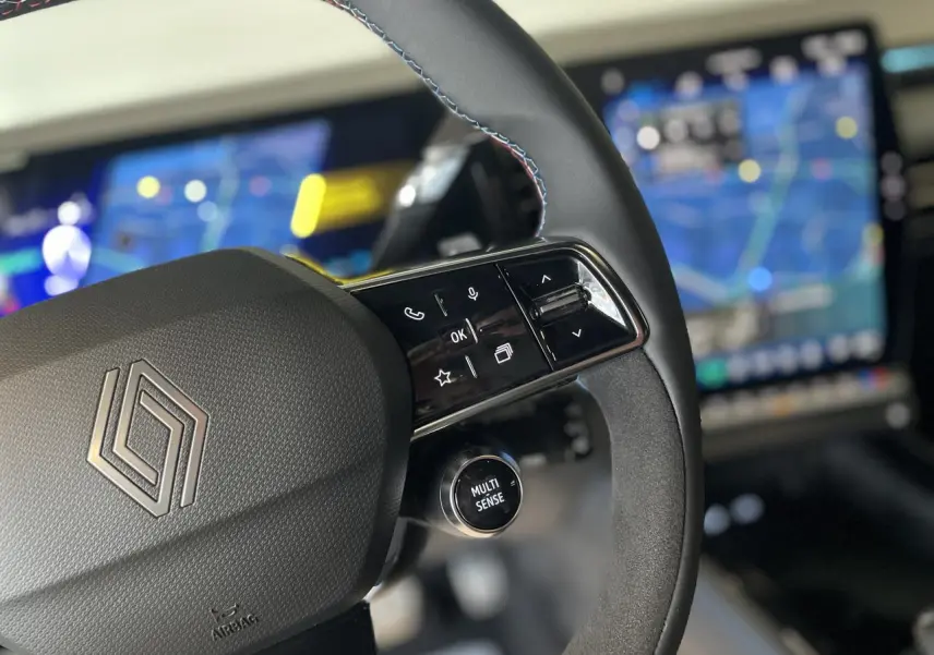 Gros plan sur le volant Alcantara avec surpiqûres tricolores et commandes multifonctions du Renault Austral Esprit Alpine.