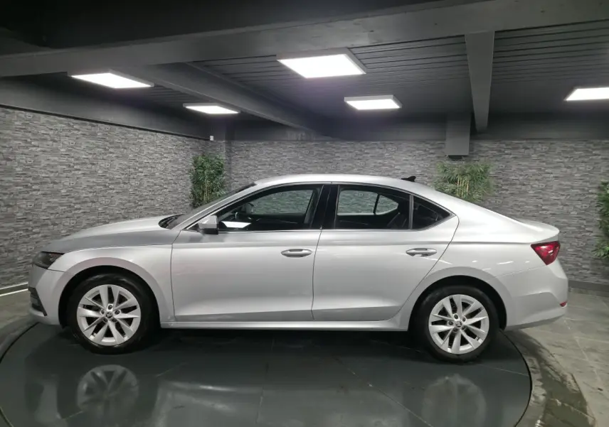 Profil côté gauche d'une Skoda Octavia gris métallisé 2023 dans un showroom avec jantes alliage 17 pouces.