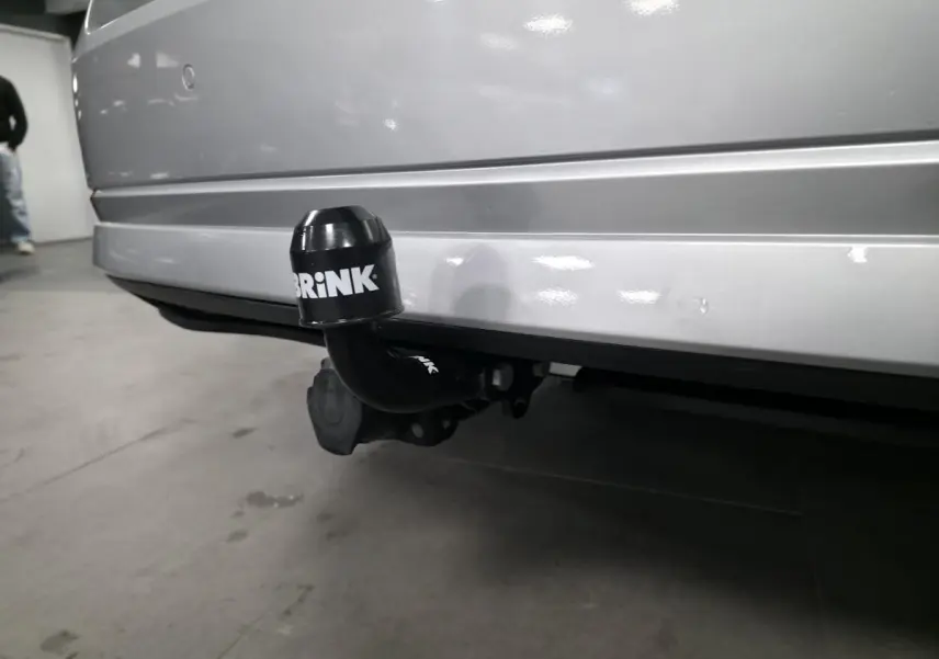 Gros plan sur l'attelage fixe noir Brink sous le pare-chocs arrière gris métallisé d'une Skoda Octavia 2023.