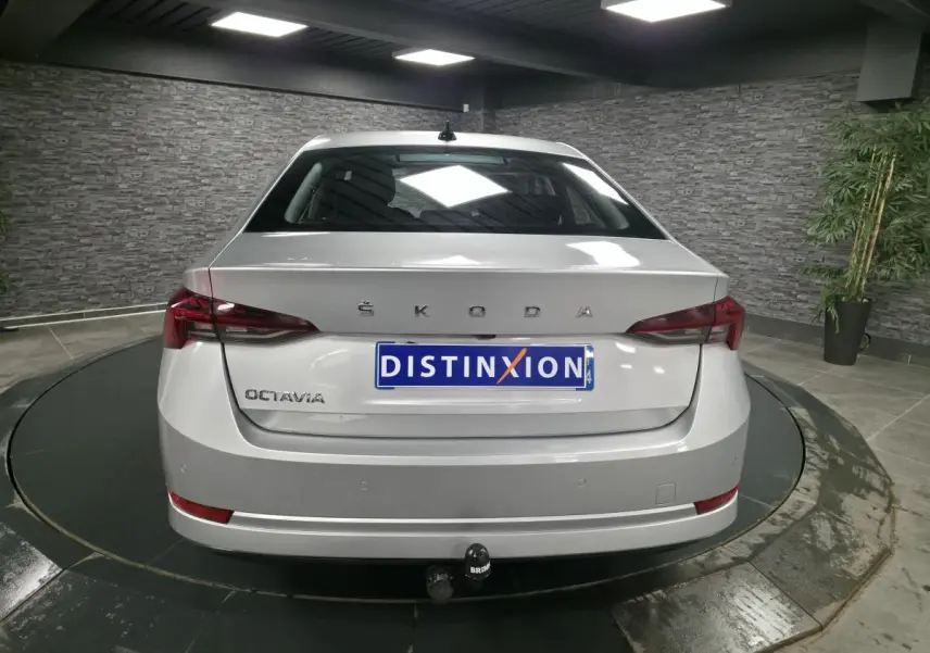 Vue arrière d'une Skoda Octavia gris métallisé avec attelage fixe et feux arrière LED dans un showroom.