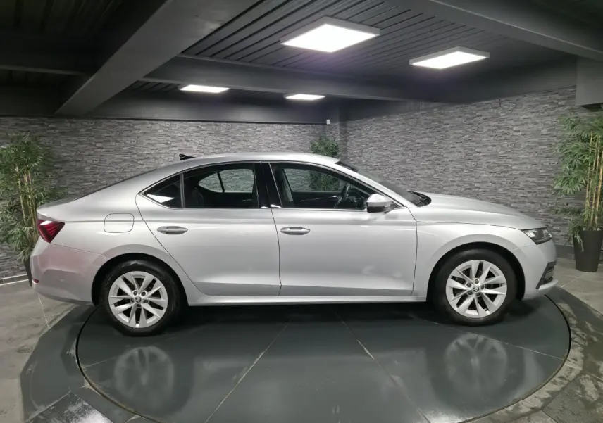 Vue latérale côté gauche d'une Skoda Octavia gris métallisé 2023 en intérieur avec jantes alliage 17 pouces.