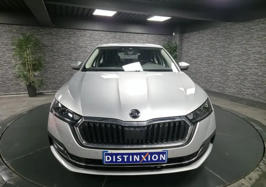 Vue avant d'une Skoda Octavia gris métallisé 2023 avec calandre noire et phares LED dans un showroom.