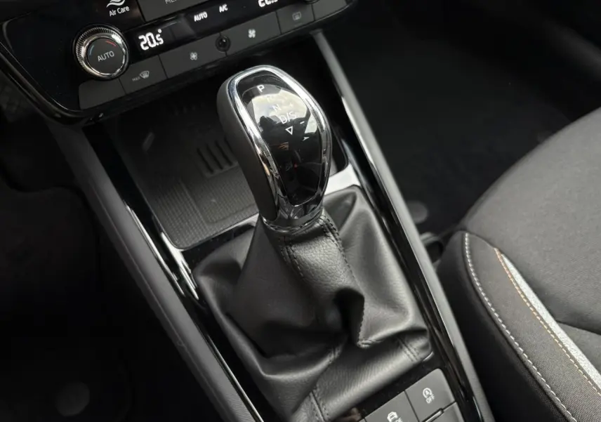 Gros plan sur la console centrale du Skoda Kamiq gris argent, mettant en valeur le levier de vitesses automatique et les commandes environnantes.