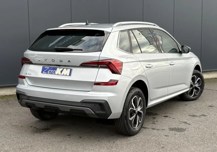 Vue 3/4 arrière droite d'un Skoda Kamiq gris argent avec vitres surteintées et jantes alliage noires.