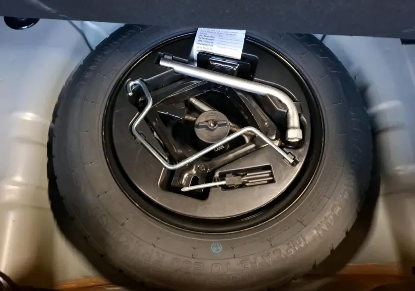 Gros plan sur la roue de secours et les outils de bord dans le coffre d'une FIAT 500 Gris Electroclash 2022.