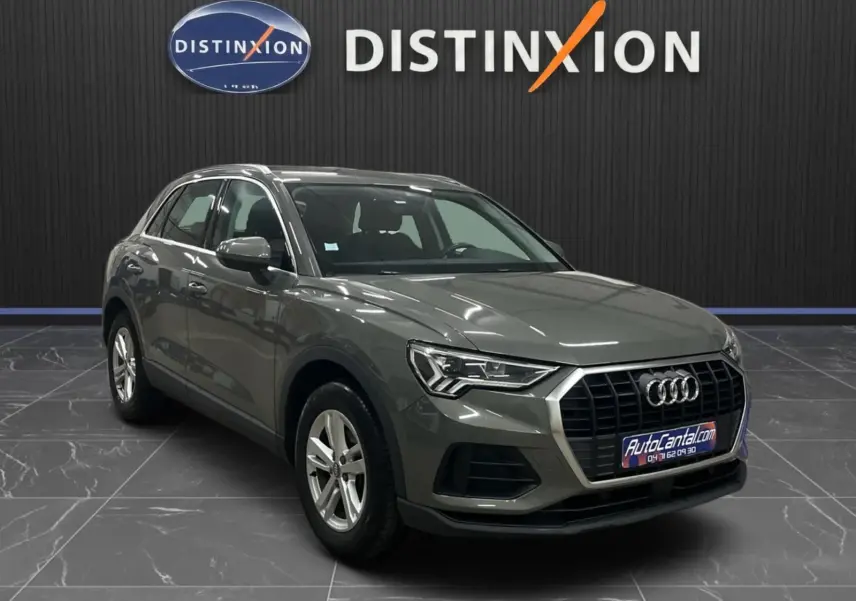 Audi Q3 Business gris en 3/4 avant droit, mettant en valeur la calandre hexagonale et les phares LED distinctifs.