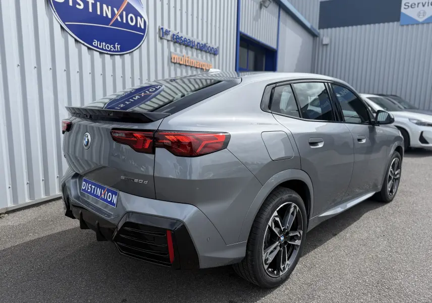 Vue 3/4 arrière droite d'une BMW X2 2.0DA 163 CH M Sport gris Skyscraper métallisé avec jantes noires et feux LED distinctifs.