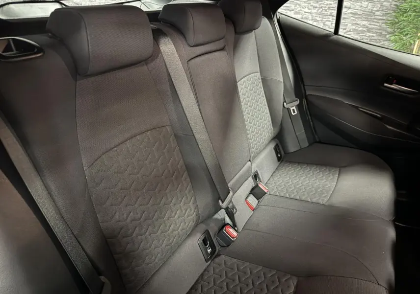 Vue intérieure de la banquette arrière en tissu noir de la Toyota Corolla hybride 2022, avec ceintures et fixations ISOFIX visibles.