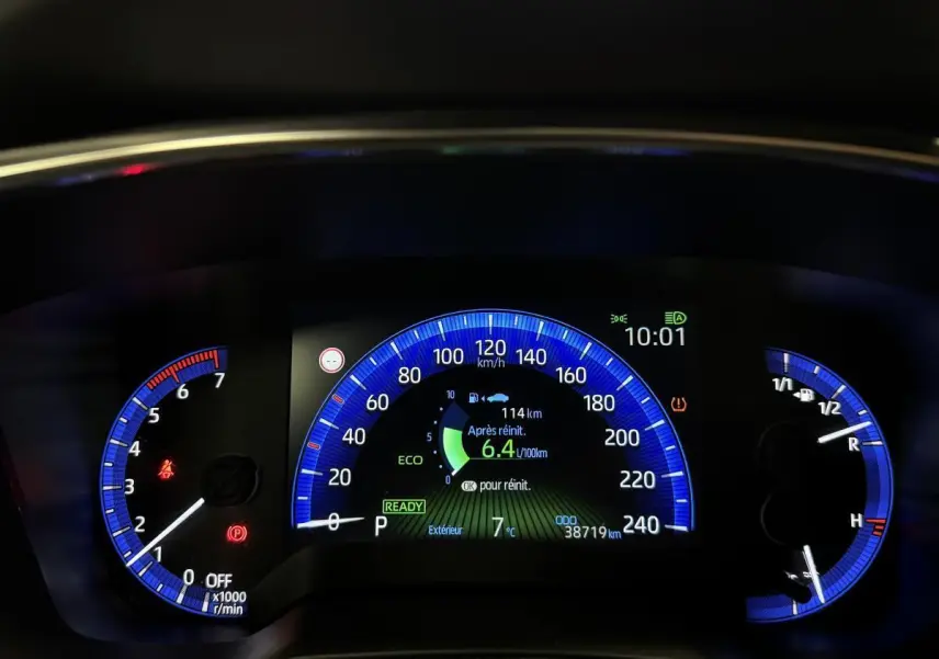 Tableau de bord numérique de Toyota Corolla hybride 2022 avec affichage bleu, consommation et vitesse en km/h.