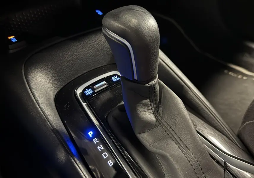 Le levier de vitesses en cuir noir de la Toyota Corolla hybride 2022 avec éclairage bleu des modes de conduite.