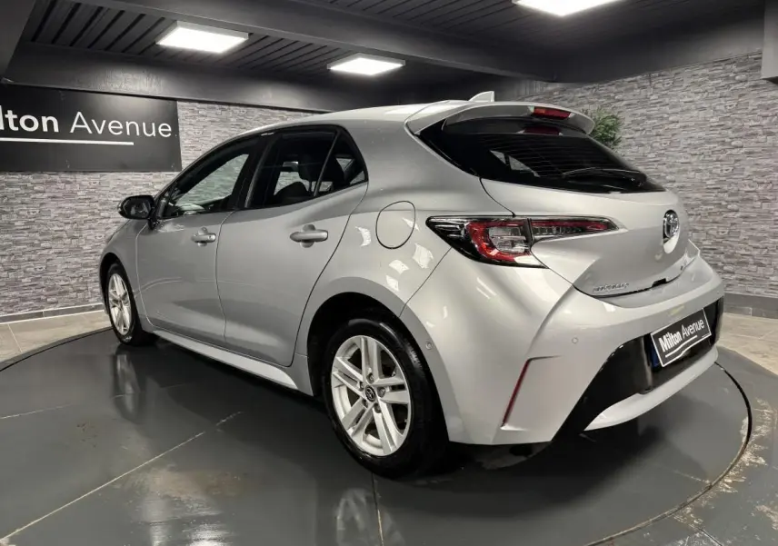 Vue 3/4 arrière droite d'une Toyota Corolla hybride 2022 gris métallisé avec jantes alliage et feux LED distinctifs.