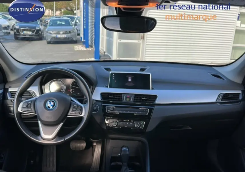 Vue intérieure frontale du tableau de bord et volant sport noir de la BMW X1 F48 LCI 2022, avec écran central et commandes climatisation.