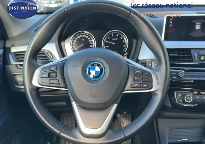 Vue centrée sur le volant sport noir de la BMW X1 2022 avec tableau de bord et écran multimédia visibles.