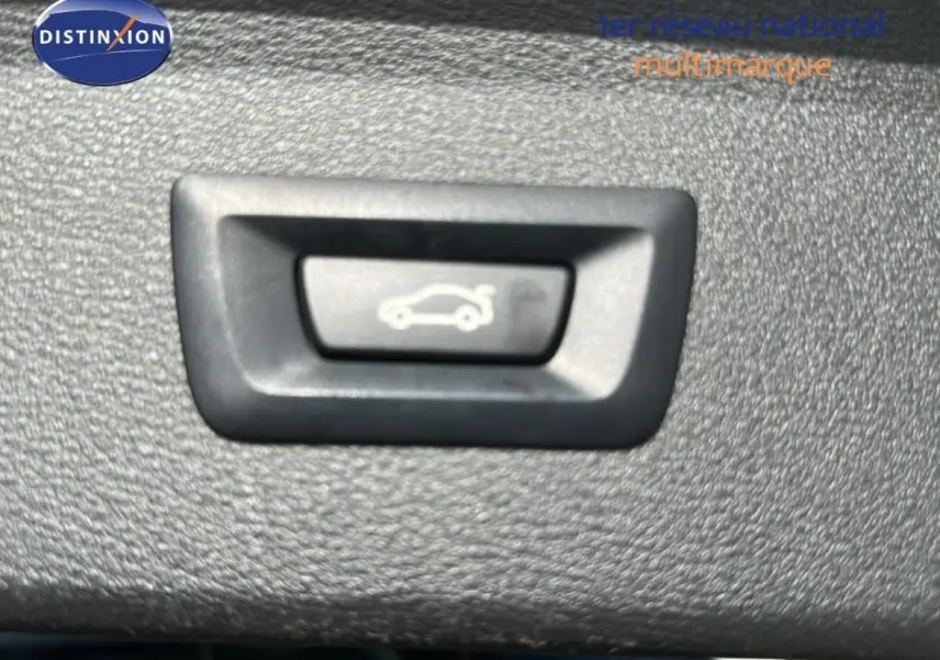 Bouton d'ouverture du coffre sur panneau intérieur d'un BMW X1 F48 LCI gris foncé, vue rapprochée.