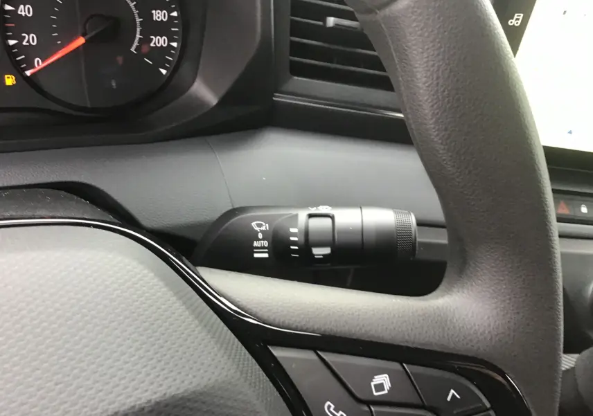 Gros plan sur le volant et la manette d’essuie-glace du Renault Master blanc, mettant en valeur les commandes intégrées au volant.