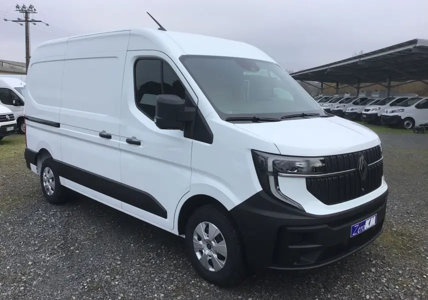 Vue 3/4 avant d’un utilitaire Renault Master blanc avec calandre noire et jantes argentées, stationné sur un sol gravillonné.