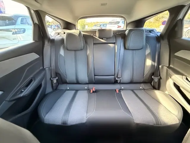 Vue intérieure arrière montrant la banquette noire en cuir et tissu du Peugeot 308 Hybrid 145 e-DCS6 Allure 2025.