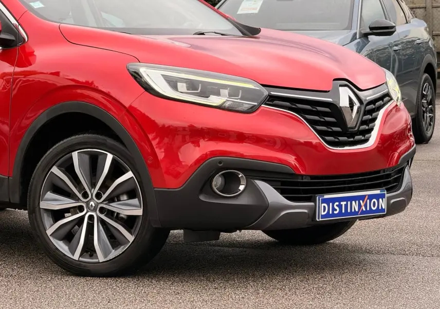 Vue 3/4 avant gauche d'un Renault Kadjar rouge flamme avec calandre noire et jantes alliage bi-ton.