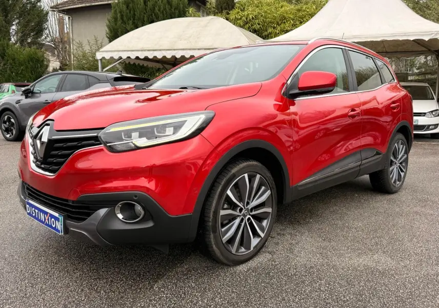Vue 3/4 avant droite d'un Renault Kadjar rouge flamme avec jantes alliage bicolores et calandre noire brillante.