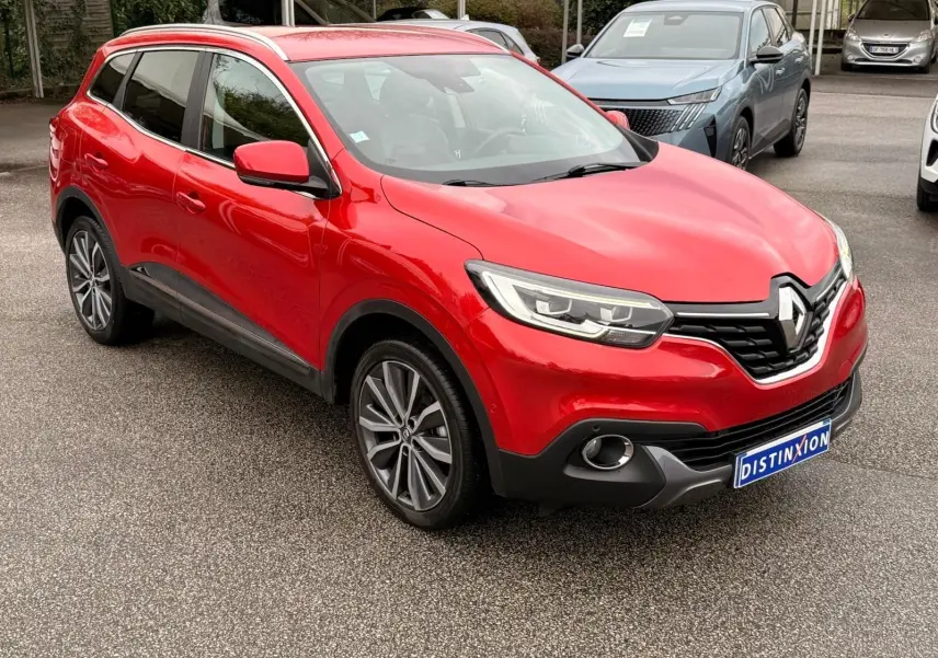 Renault Kadjar rouge flamme en 3/4 avant droit, avec calandre noire et jantes alliage bicolores visibles.