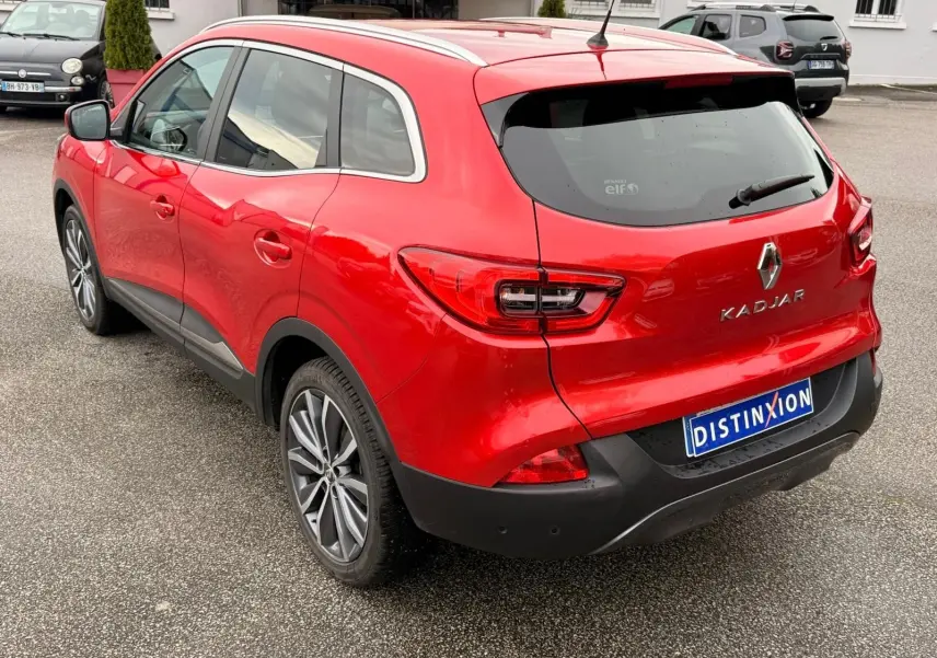 Vue 3/4 arrière droite d’un Renault Kadjar rouge flamme avec jantes alliage bicolores et toit panoramique.