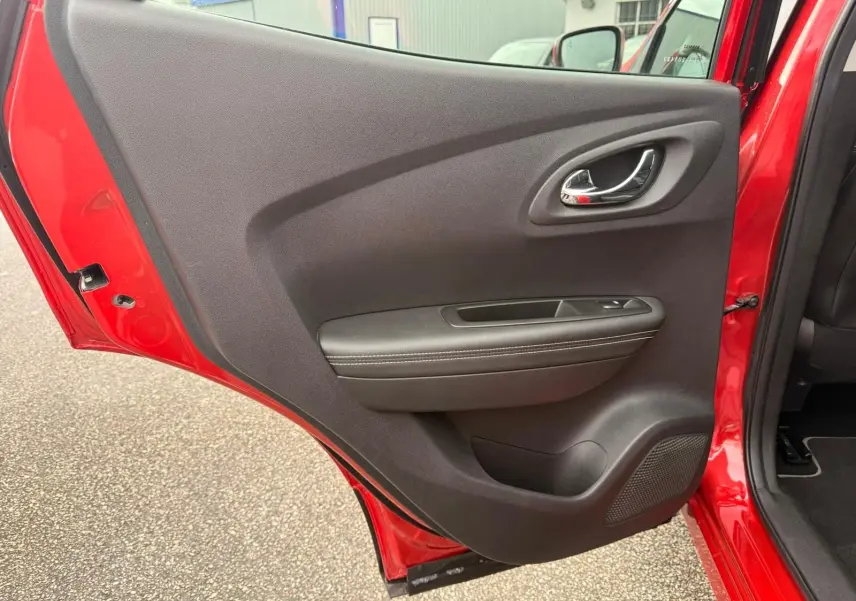 Vue rapprochée de la porte arrière gauche rouge flamme d’un Renault Kadjar 2016 avec garniture noire et poignée chromée.