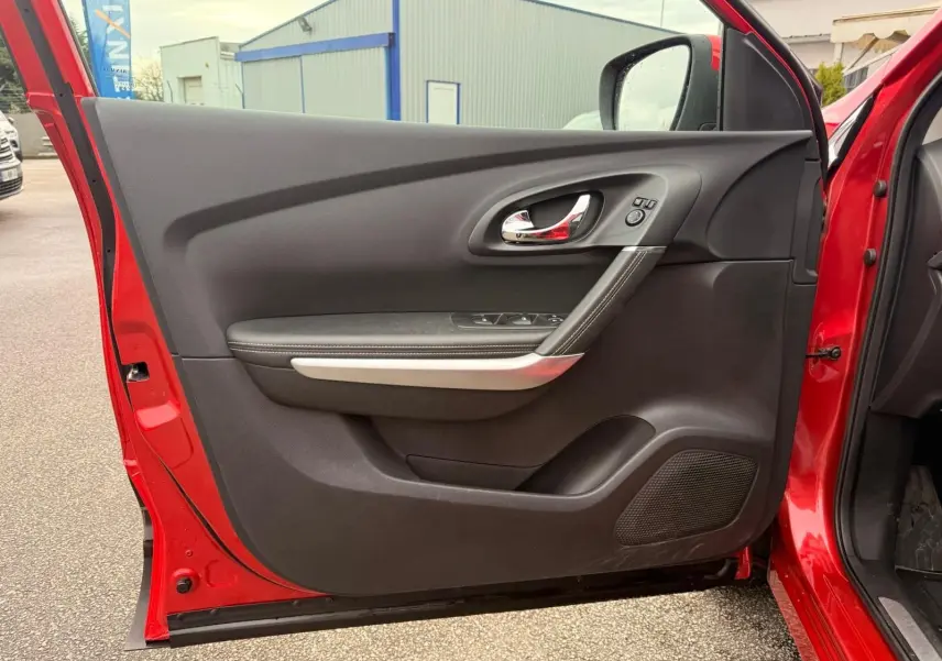 Vue intérieure de la porte avant gauche rouge flamme du Renault Kadjar 2016, avec poignée chrome et commandes électriques.