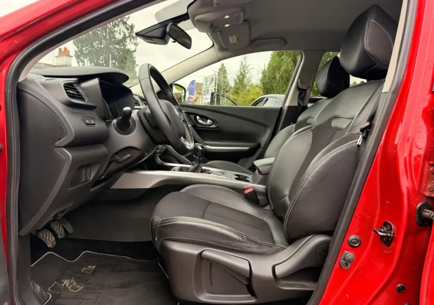 Intérieur côté conducteur du Renault Kadjar rouge flamme 2016, sièges cuir noir et tableau de bord moderne.