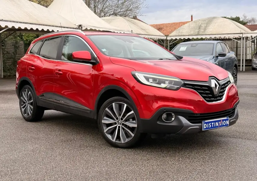 Renault Kadjar rouge flamme en 3/4 avant droit, avec jantes alliage bi-ton et calandre noire distinctive.