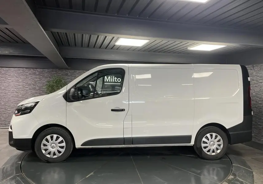 Profil côté gauche du fourgon blanc Nissan Primastar N-Connecta 2022 avec enjoliveurs de roues et protections noires.